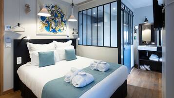 A hotel room with a large bed, a bathroom with a mirror and sink, and a painting on the wall.