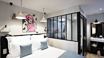 Un dormitorio moderno con una cama grande, lámparas de noche, una obra de arte en la pared y vista al baño a través de una puerta de vidrio.