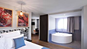 Una habitación de hotel moderna con una cama grande, baño independiente con bañera y obras de arte en las paredes.
