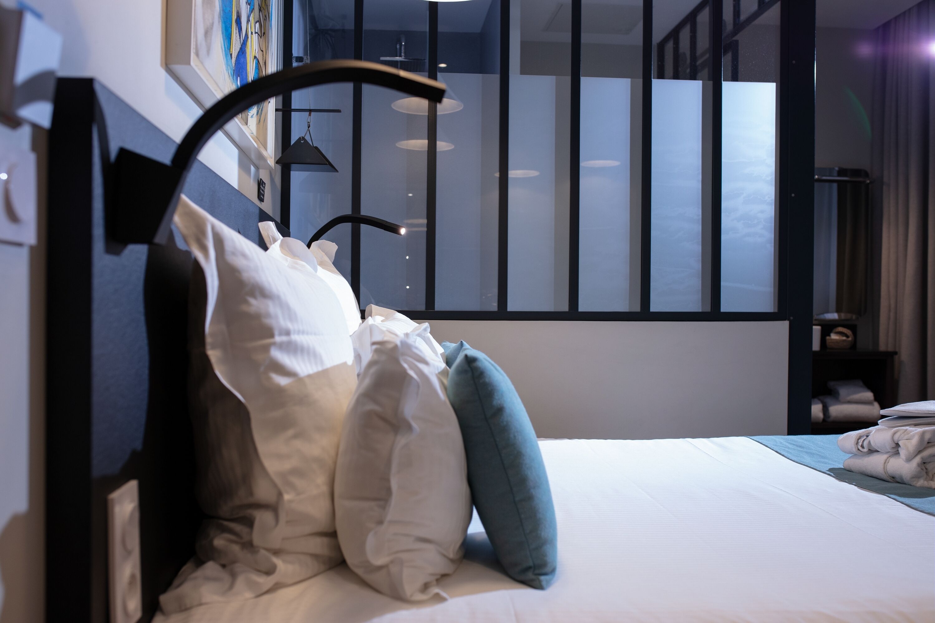A neatly made bed with pillows, a bedside table, and a lamp.