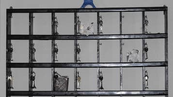 A metal rack with numbered slots holding various keys and a small Eiffel Tower model.