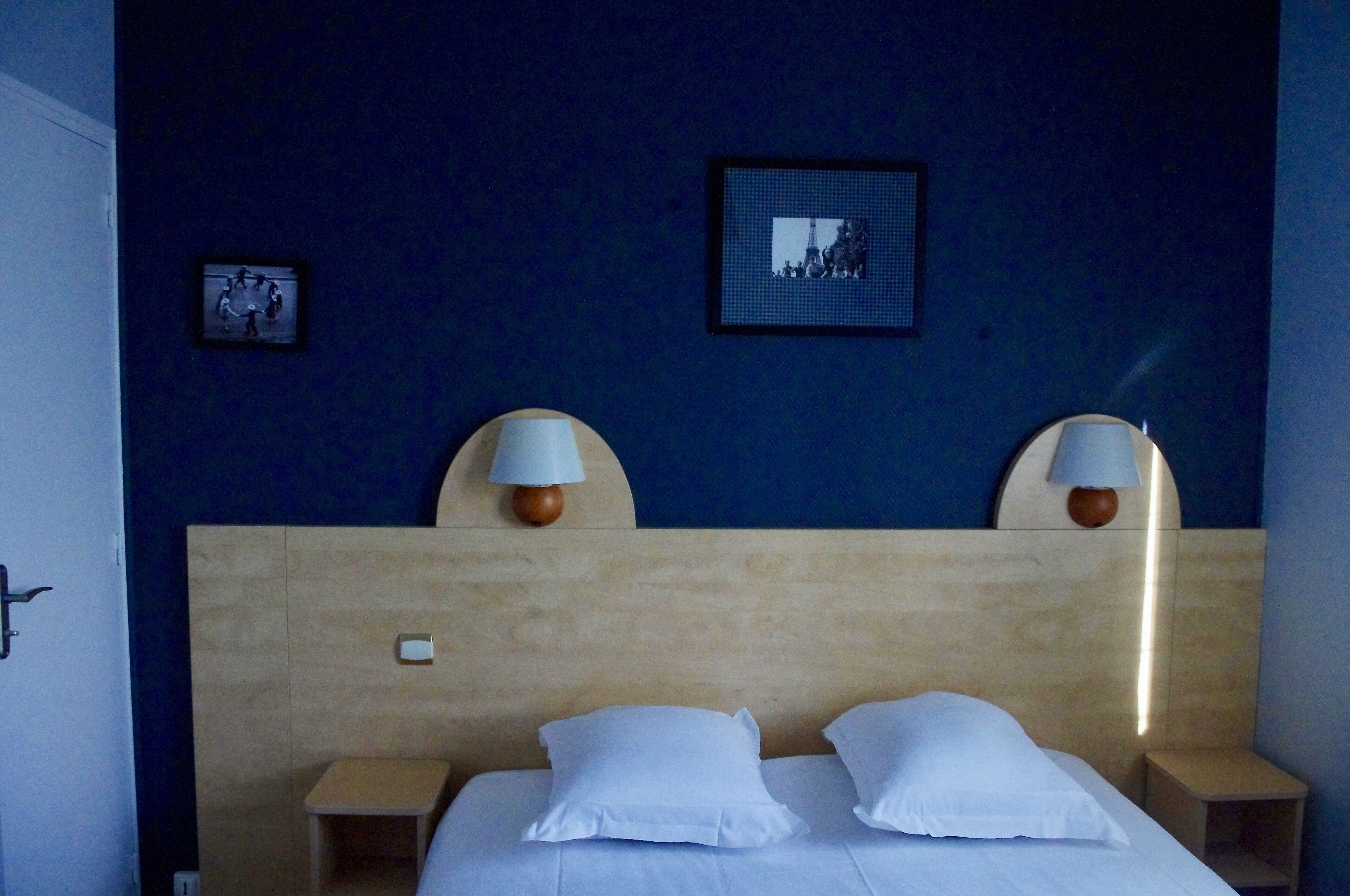 Een hotelkamer met een groot bed, twee bedlampen, een ingelijste foto aan de muur en een klein tafeltje.