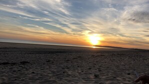 Una playa con un atardecer, arena y un horizonte lejano.