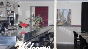 Un área de bar moderna con un cartel de 'Welcome', una máquina de café y una planta en maceta.