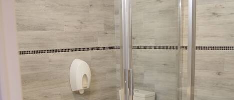 Un baño con cabina de ducha de vidrio, inodoro y lavabo.