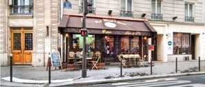Un café con terraza, menú en una pizarra y un cartel que indica zona para fumadores.