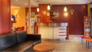 Un hall de hotel con recepción, zona de estar y estantería.