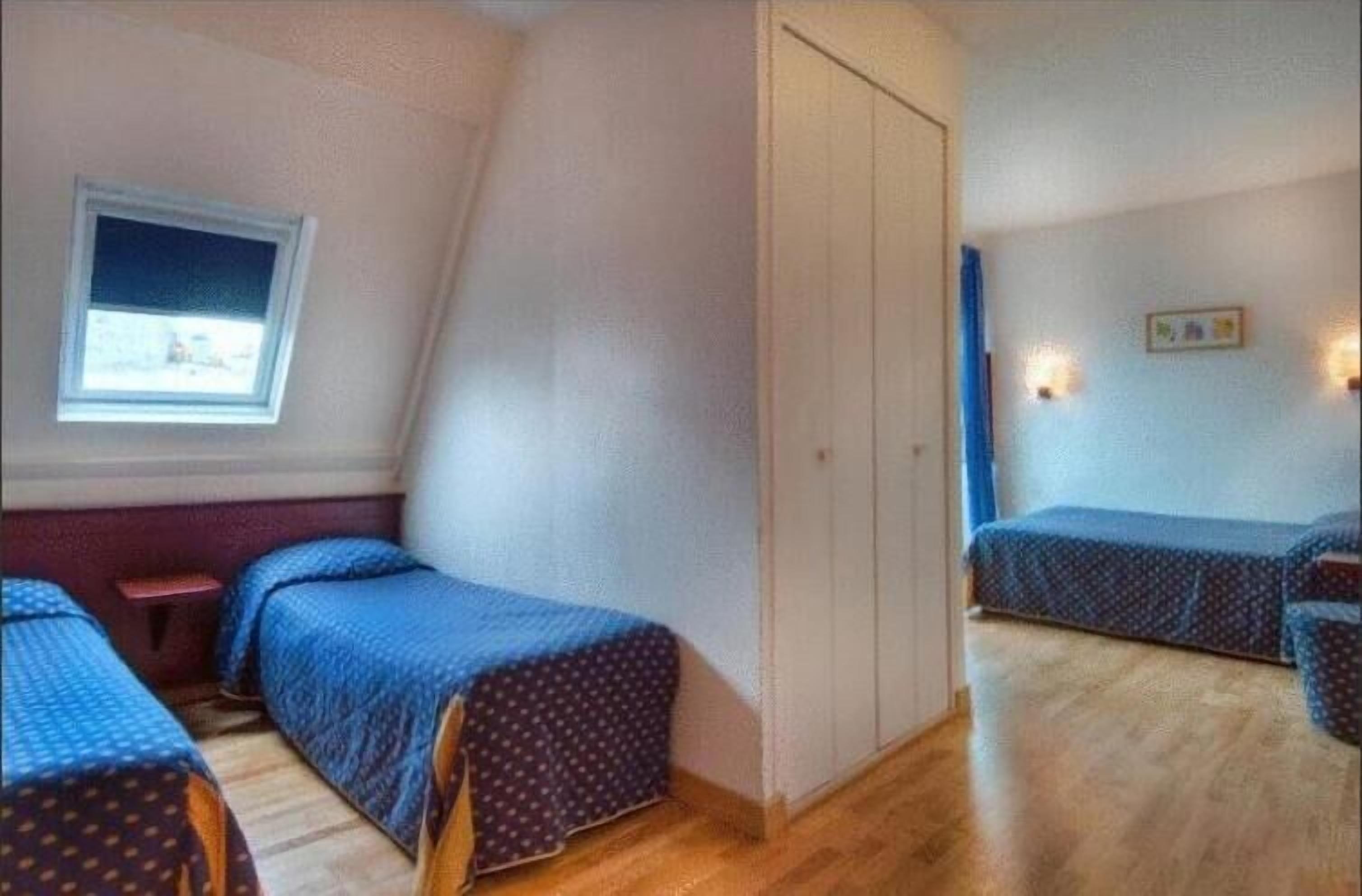 Et værelse med to senge, et vindue, et skab og et lille bord.