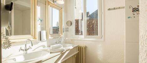 A bathroom with a double sink, a mirror, a window, and a radiator.