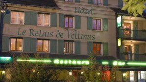 Ein Hotel namens "Le Relais de Vellnus" mit einer klassischen Fassade, mehreren Fenstern und einer grünen Markise.