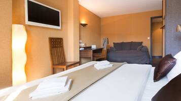 A hotel room with a bed, a desk, a chair, a TV, and a mirror.