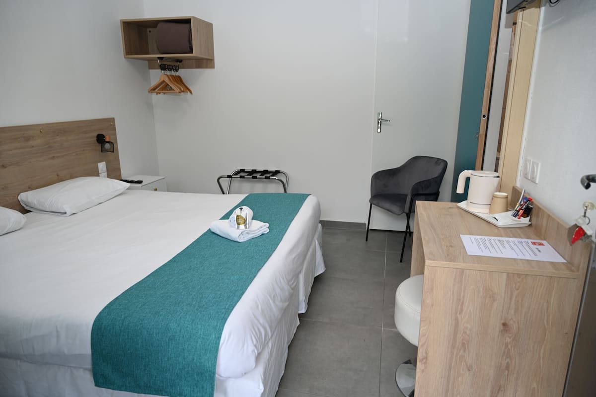 Habitació d'hotel amb llit, escriptori, cadira, taula petita i mirall.