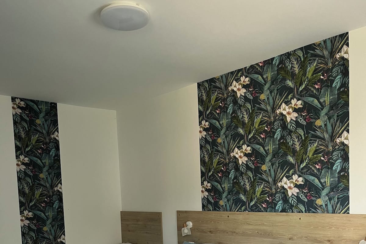 Una habitació d'hotel amb dos llits, un mural floral gran a la paret i una làmpada al sostre.