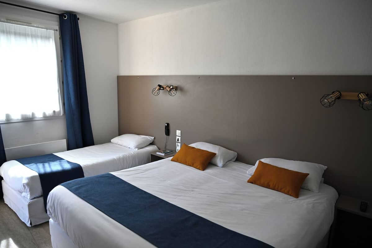 Habitació d'hotel amb dos llits, una taula de nit amb una làmpada, un telèfon i una làmpada de paret.
