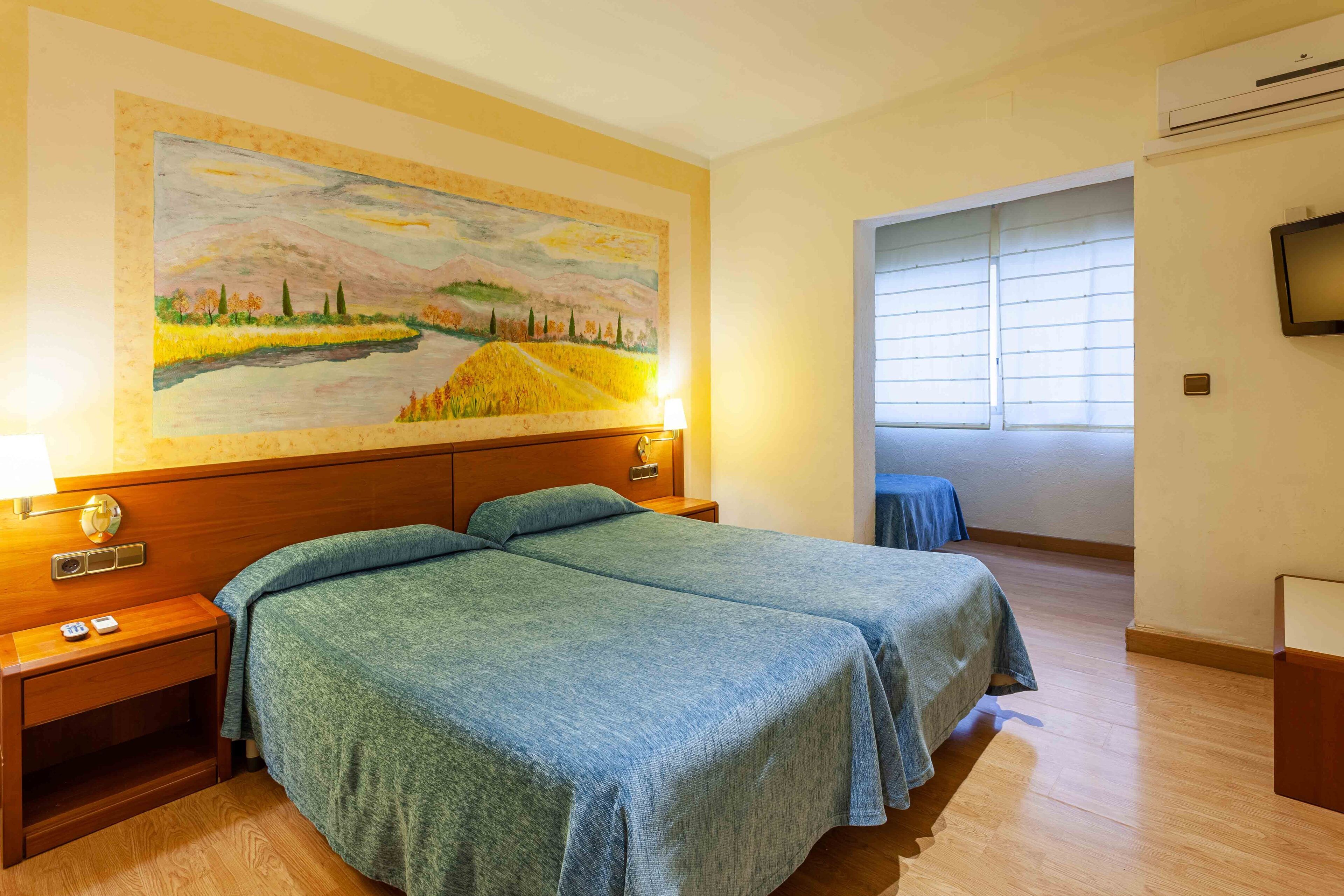 A hotel room with two beds, a painting on the wall, a TV, and a window with blinds.