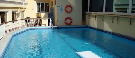 Una piscina al aire libre, sillones reclinables de piscina