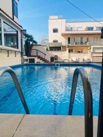 Una piscina al aire libre, sillones reclinables de piscina