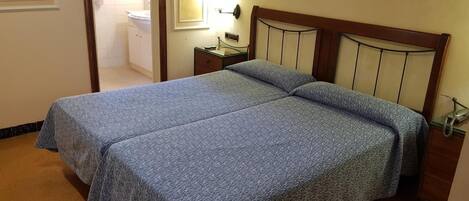 A room with a double bed, a bedside table, and a nightstand.