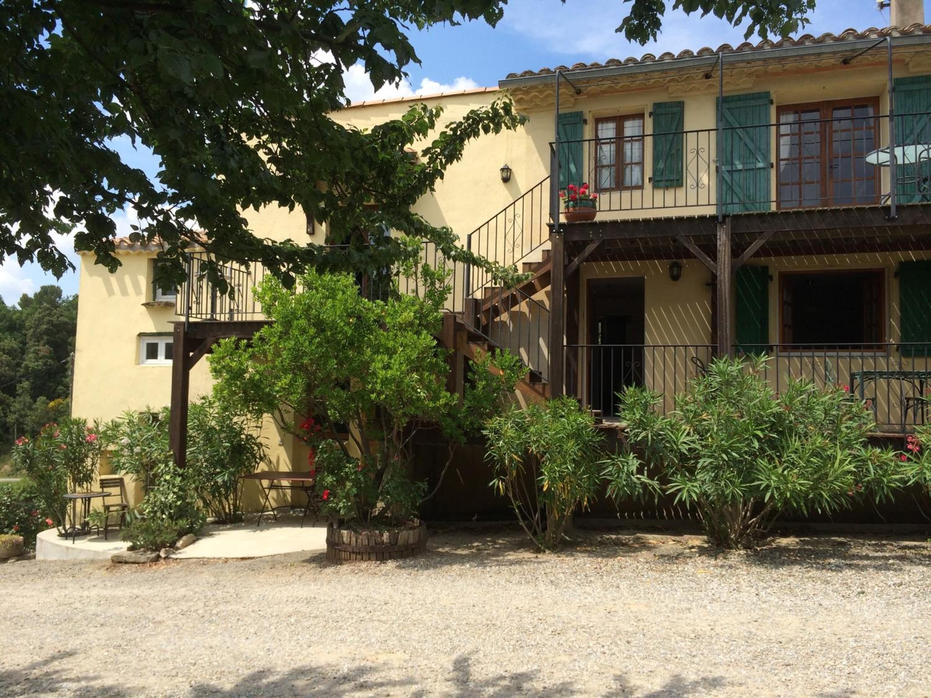 Un bâtiment à deux étages doté d’un balcon, d’un petit jardin et d’une allée gravillonnée.