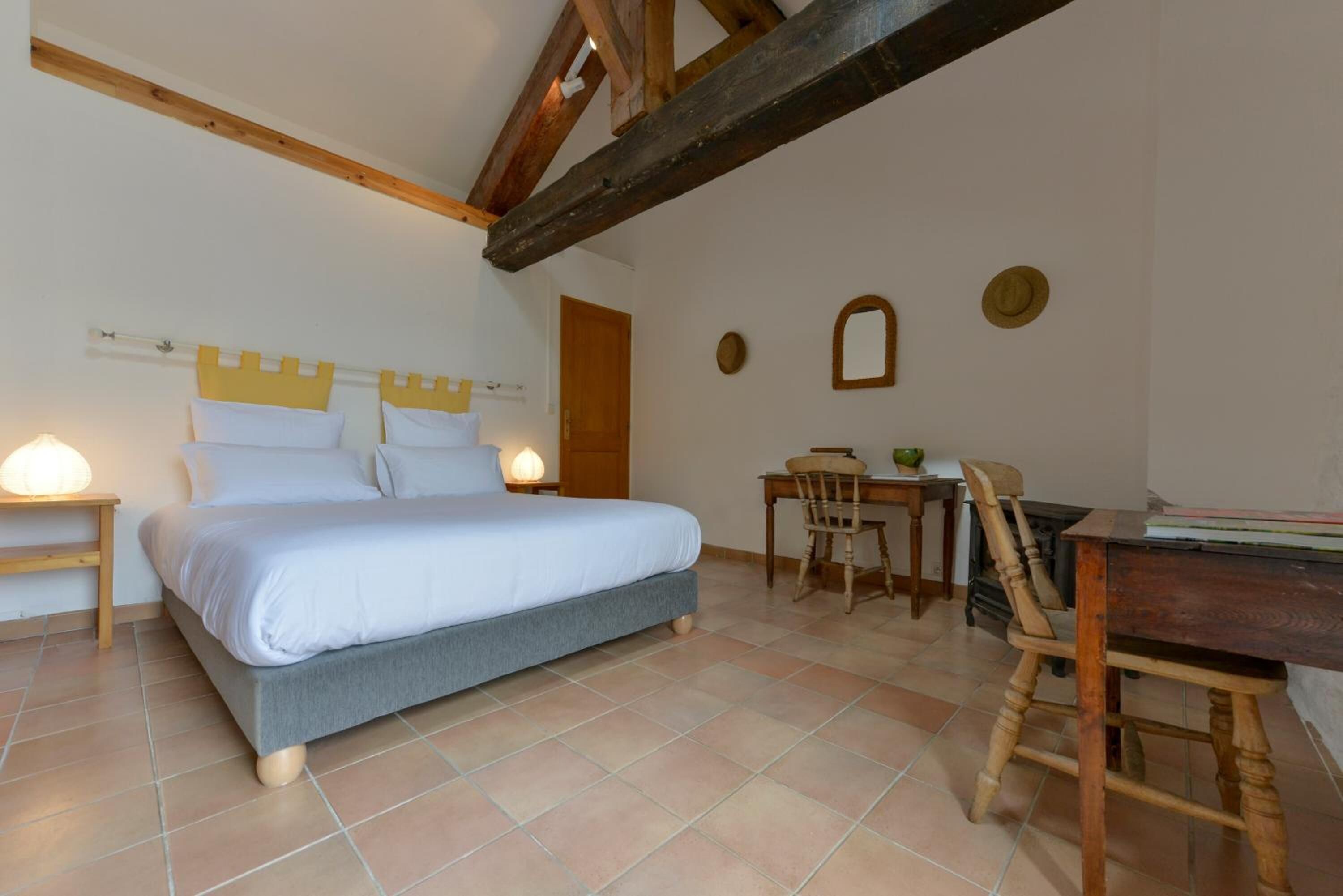 A bedroom with a bed, bedside tables, a desk, and chairs.