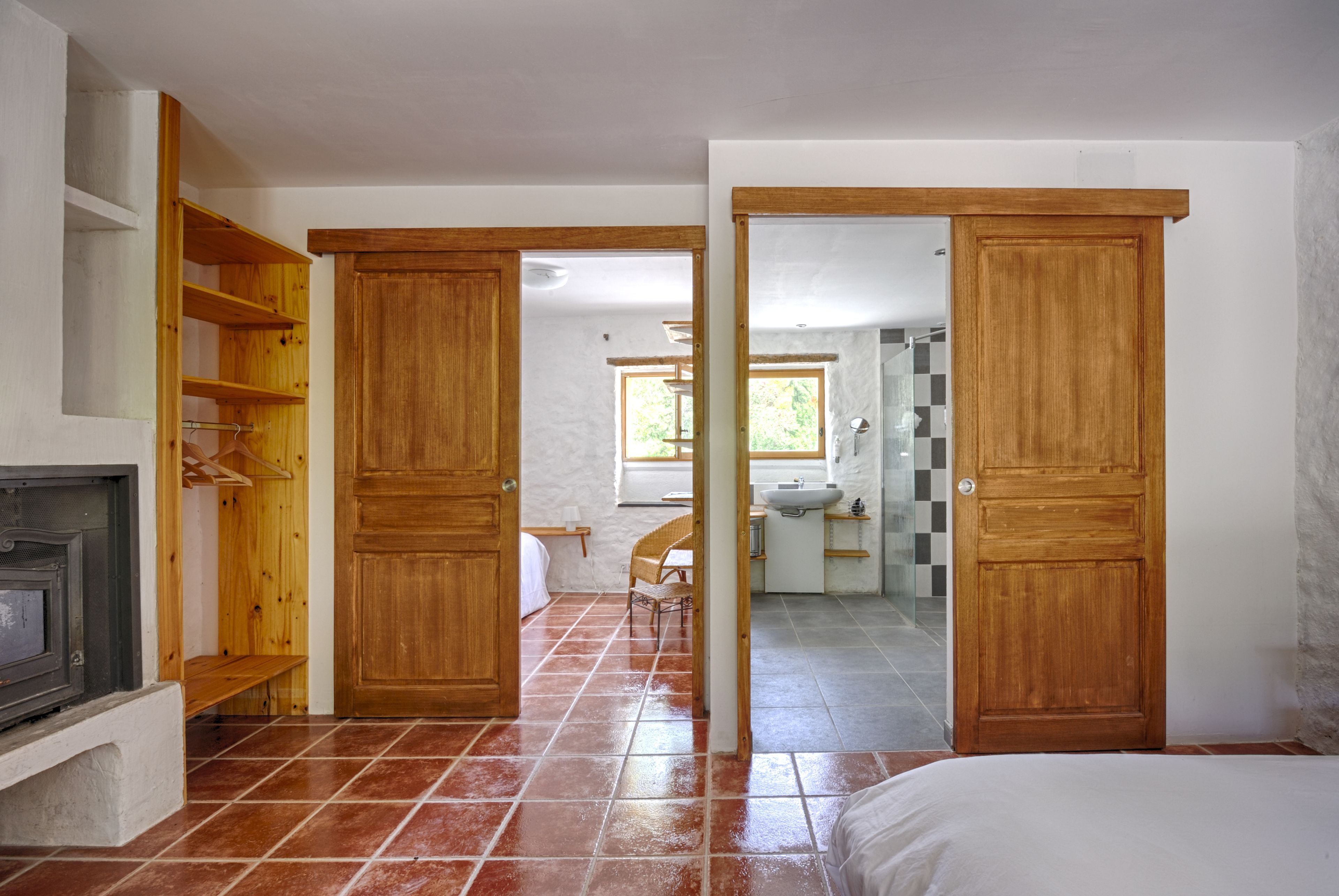 Une pièce avec une armoire en bois, un lit et une salle de bain visible à travers une porte ouverte.