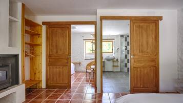 Une pièce avec une armoire en bois, un lit et une salle de bain visible à travers une porte ouverte.