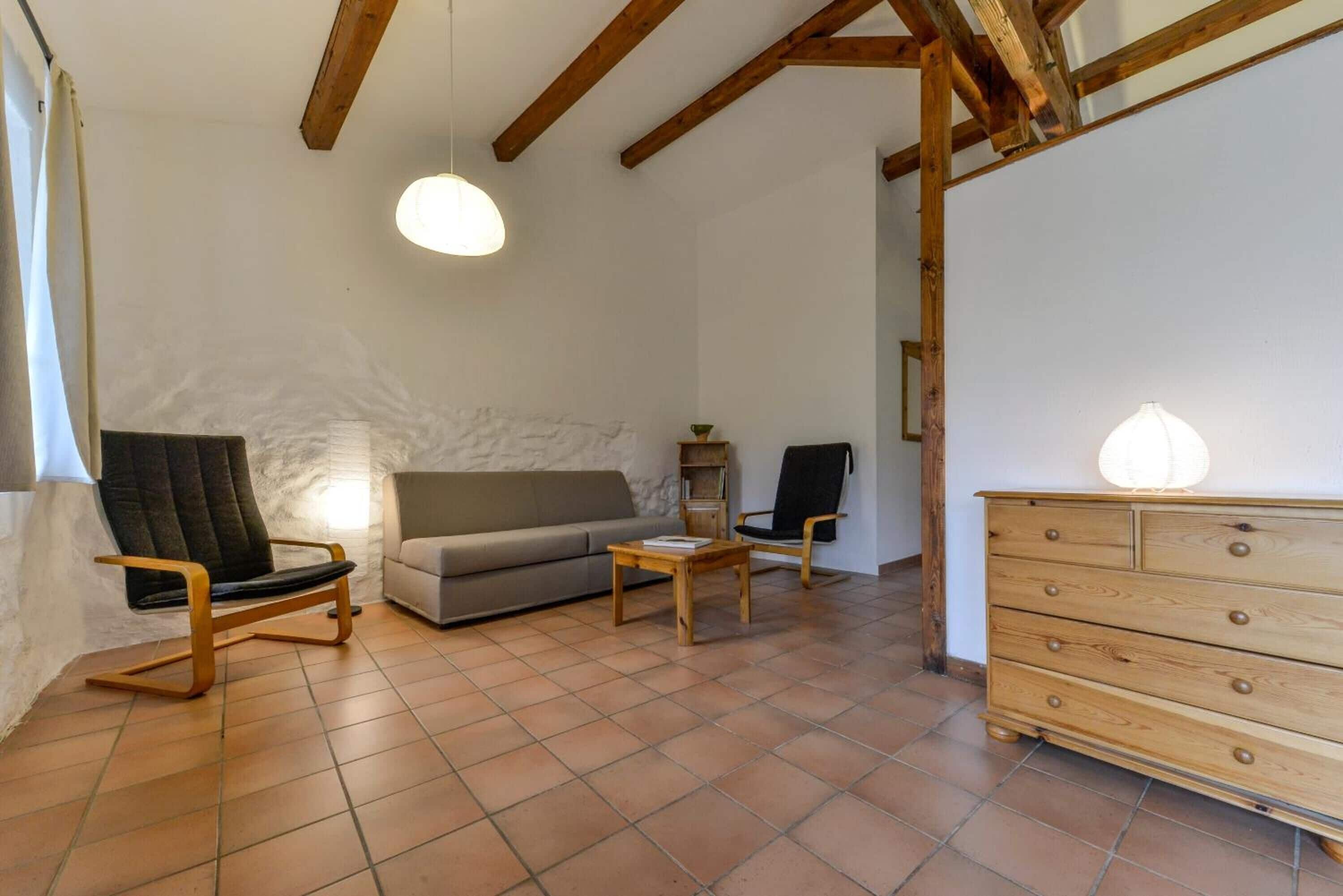 Ein Wohnzimmer mit einer Couch, zwei Sesseln, einer Holzkommode und einem Fliesenboden.