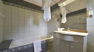 A modern bathroom with a bathtub, a vanity with a mirror, and a shower area.