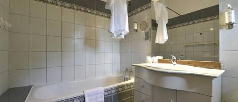 Un baño moderno con bañera, tocador con espejo y zona de ducha.