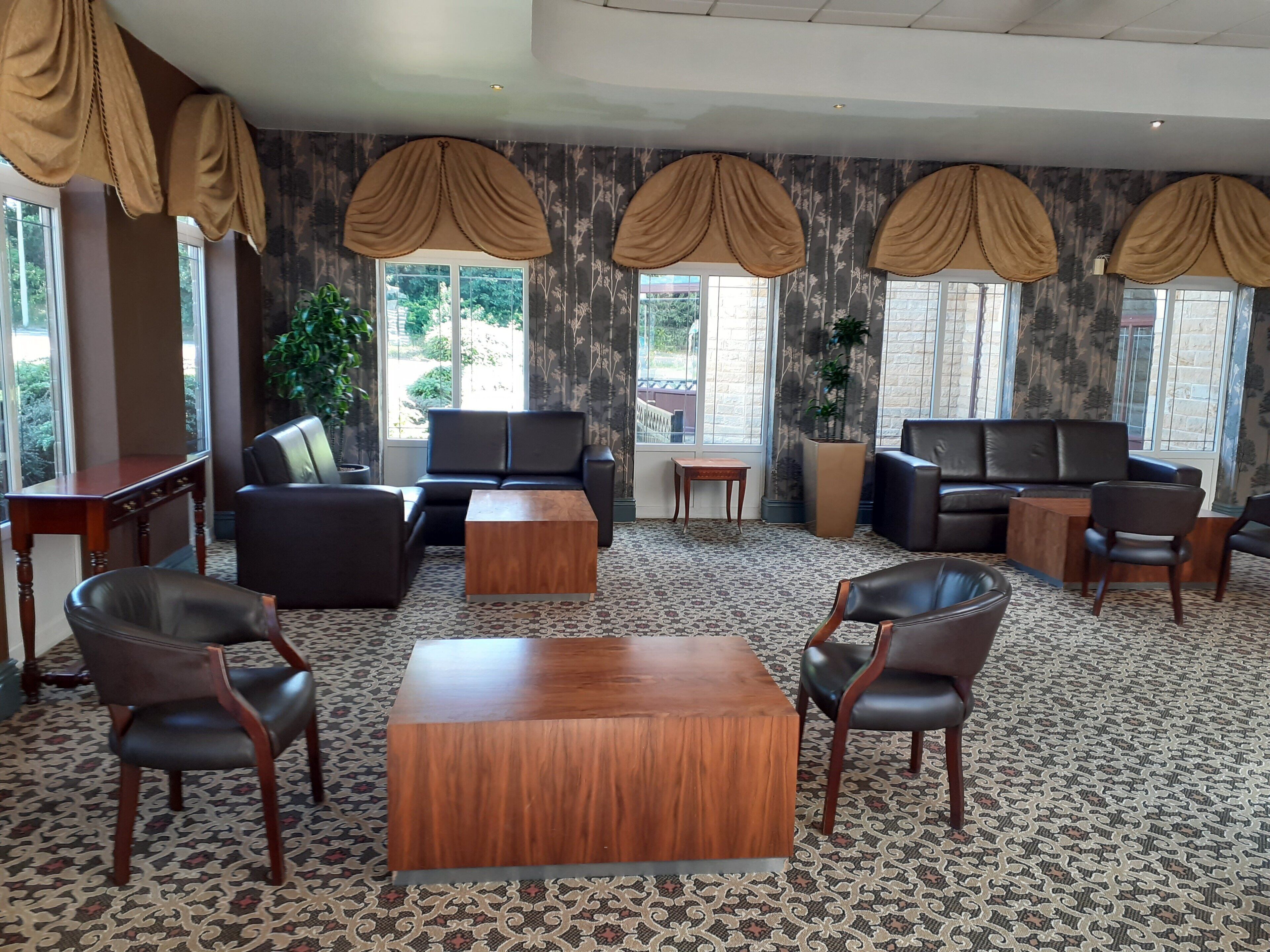 A hotel lobby with a sofa set, a coffee table, and a patterned carpet.