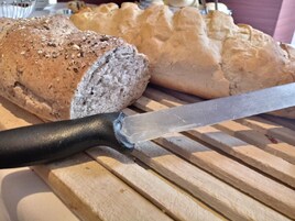 Una hogaza de pan y un cuchillo sobre tabla de madera.