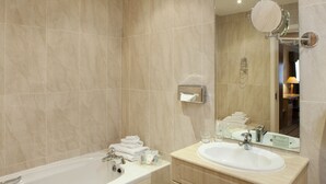 A modern bathroom with a bathtub, a sink, and a mirror.