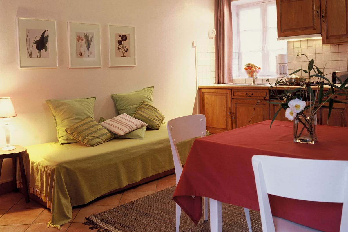 Una habitació acollidora amb un llit, una taula de menjador i una zona de cuina.