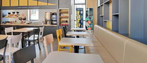 A modern cafe with multiple seating areas, including tables and booths, and a counter with a coffee machine.