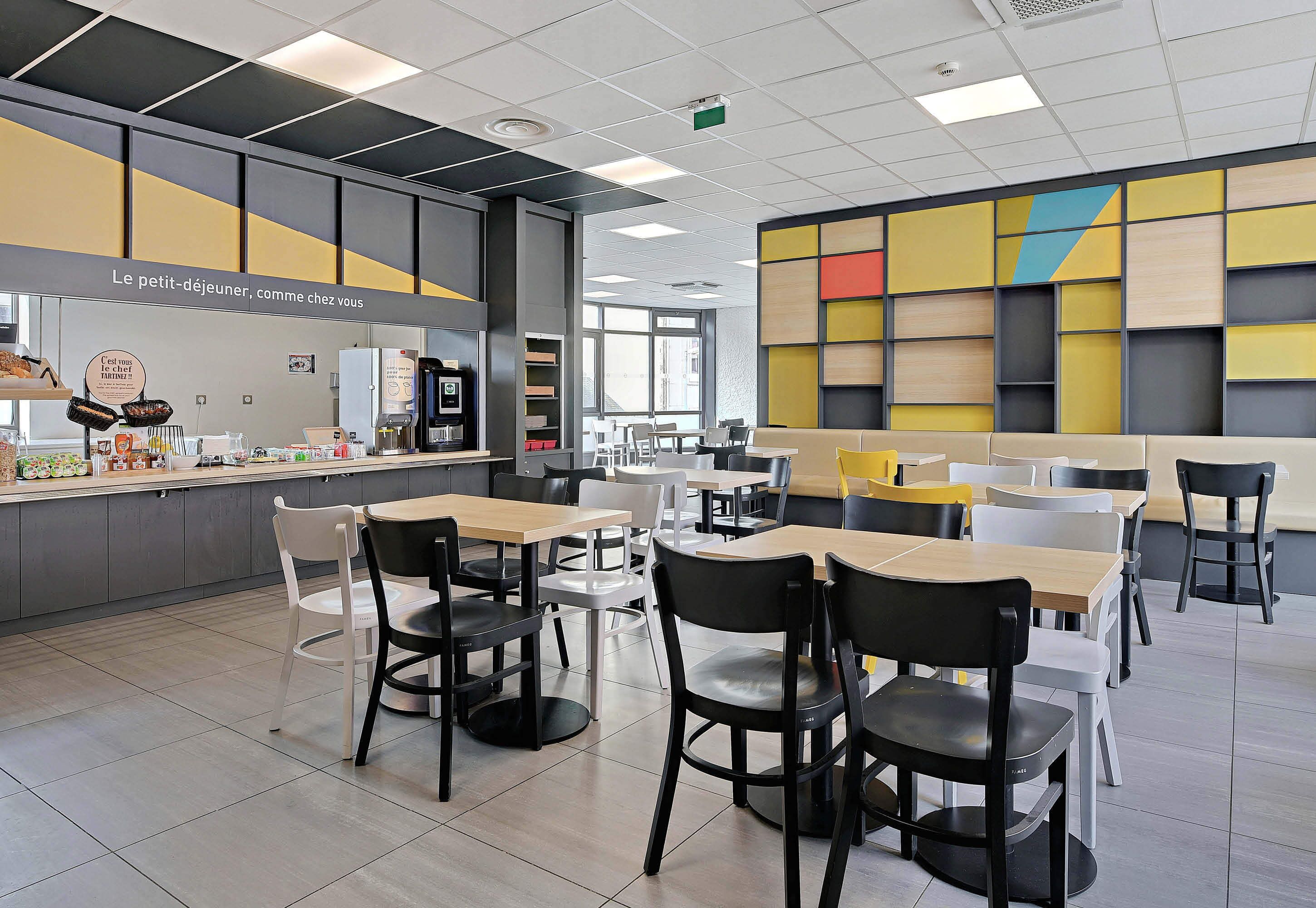 Un café moderno con mostrador, zona de estar y una pared colorida.