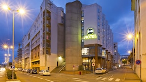 A hotel with a prominent 'HOTEL' sign, multiple floors, and a parking area with cars. - B&B HOTEL LE MANS Centre (Le Mans)
