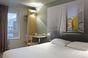 Une chambre d’hôtel équipée d’un lit, d’un bureau, d’une chaise, d’une fenêtre avec des rideaux et d’une lampe fixée au mur.