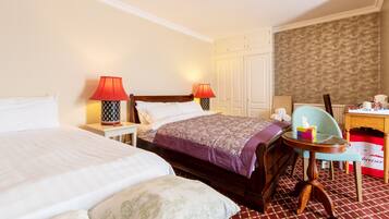 A hotel room with two beds, a desk, a chair, and a small table.