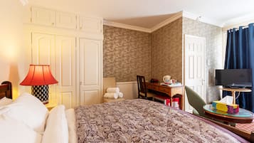 Habitación de hotel con una cama grande, un escritorio con silla, televisión y un baño visible a través de una puerta abierta.
