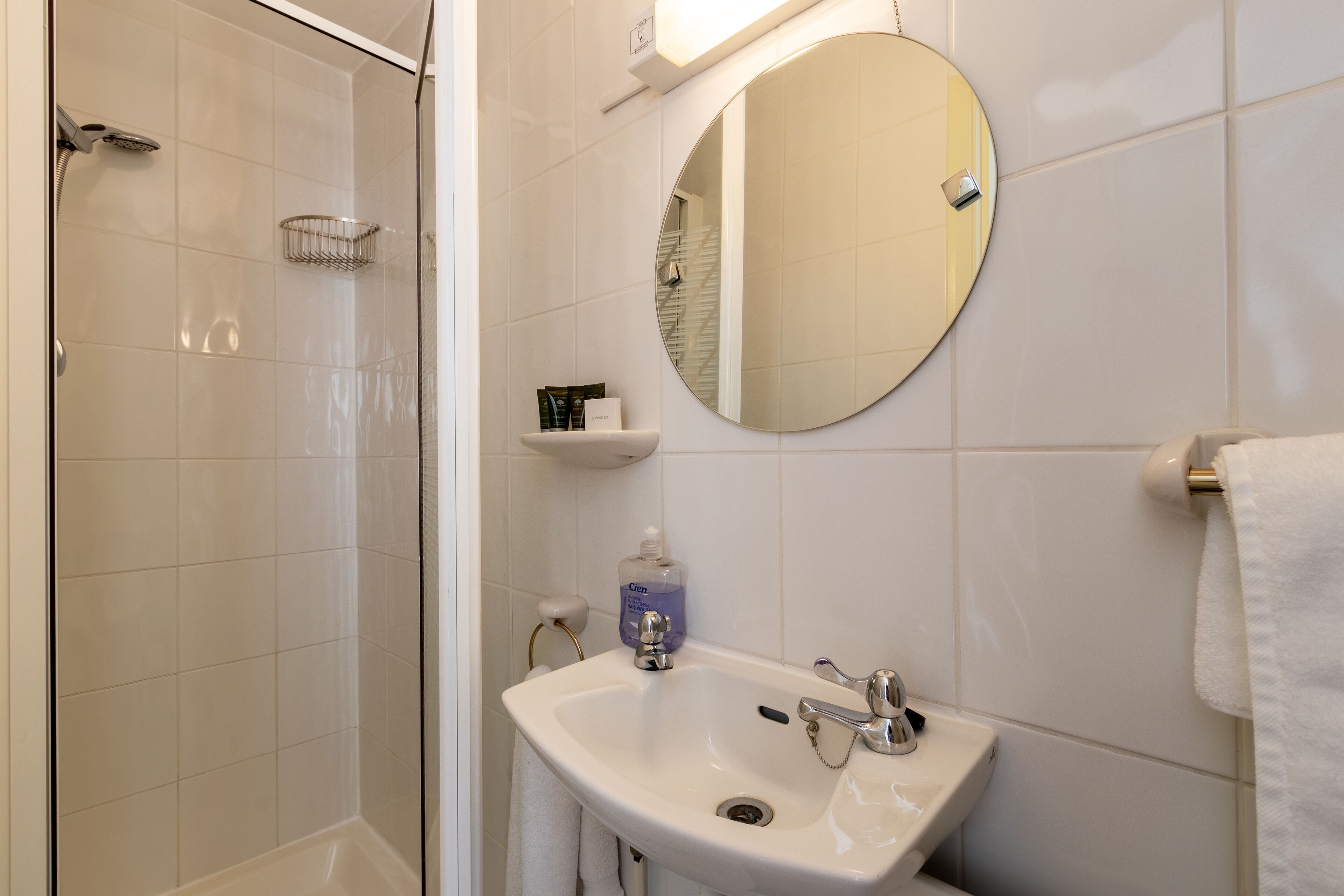 Un baño con ducha, lavabo y espejo.