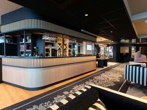 Un espace bar moderne avec un comptoir incurvé, des étagères remplies de bouteilles et des verres suspendus.