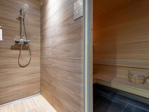 Una sauna con paneles de madera, un cabezal de ducha y un banco de madera.
