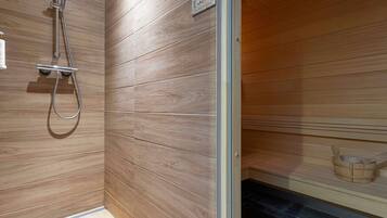 Una sauna con paneles de madera, un cabezal de ducha y un banco de madera.