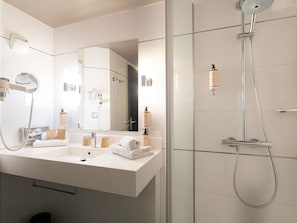 Un baño moderno con lavamanos doble, espejo, ducha de mano y perchero.