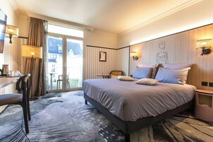 Quarto de hotel com uma cama grande, uma escrivaninha, uma cadeira e vista para o exterior.