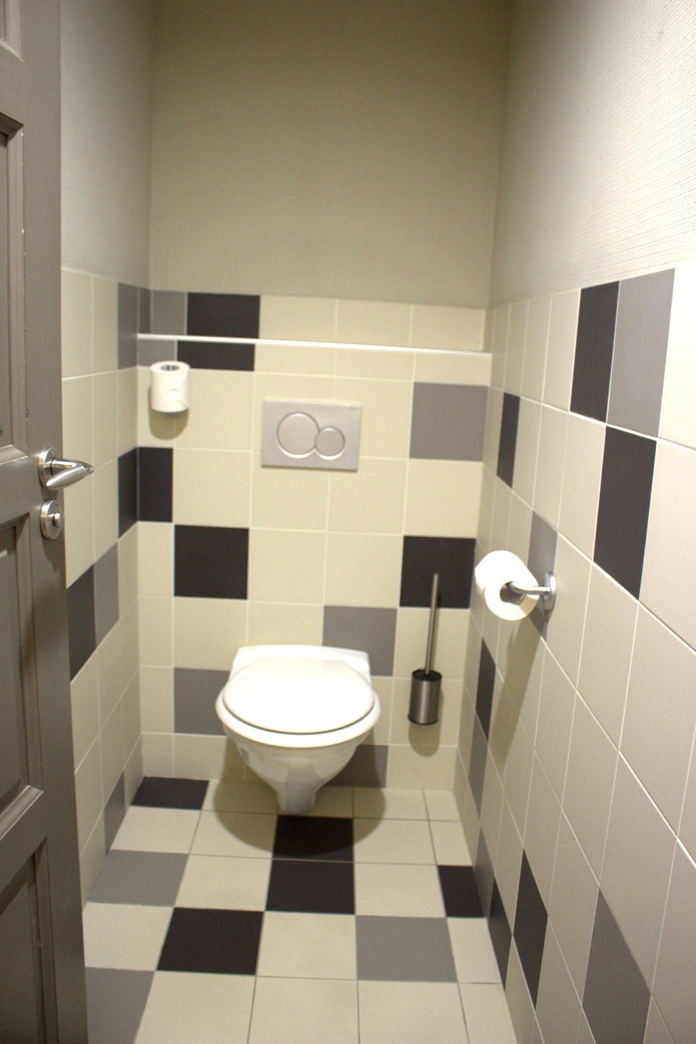 Un baño pequeño con inodoro, dispensador de papel higiénico y secamanos.