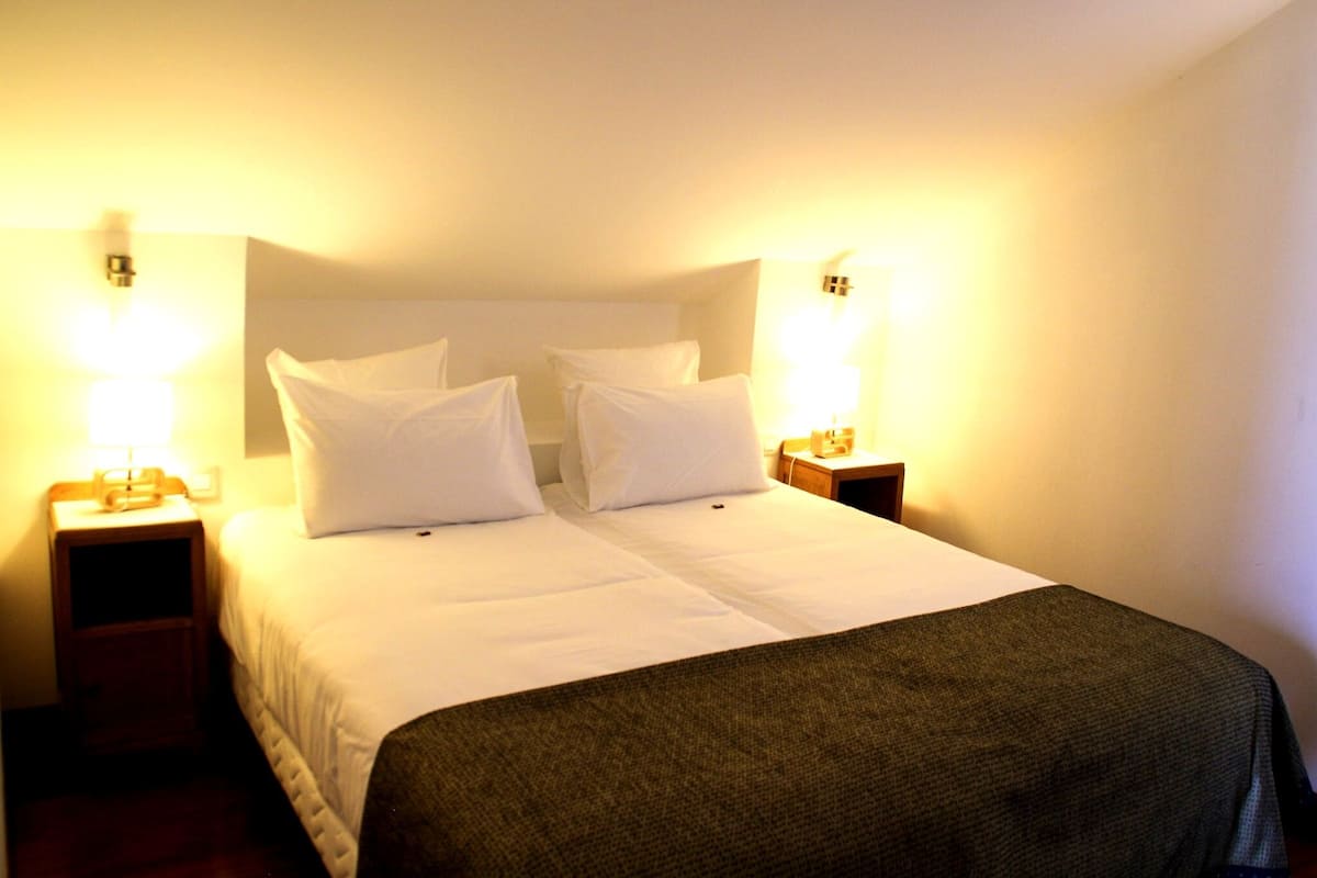 Ein Hotelzimmer mit einem Doppelbett, zwei Nachttischen und zwei Wandlampen.