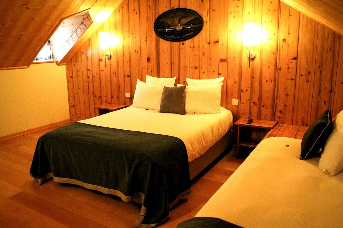 Ein Zimmer mit einem Bett, einem Nachttisch, einer Wanduhr und einer Holzbalkendecke.