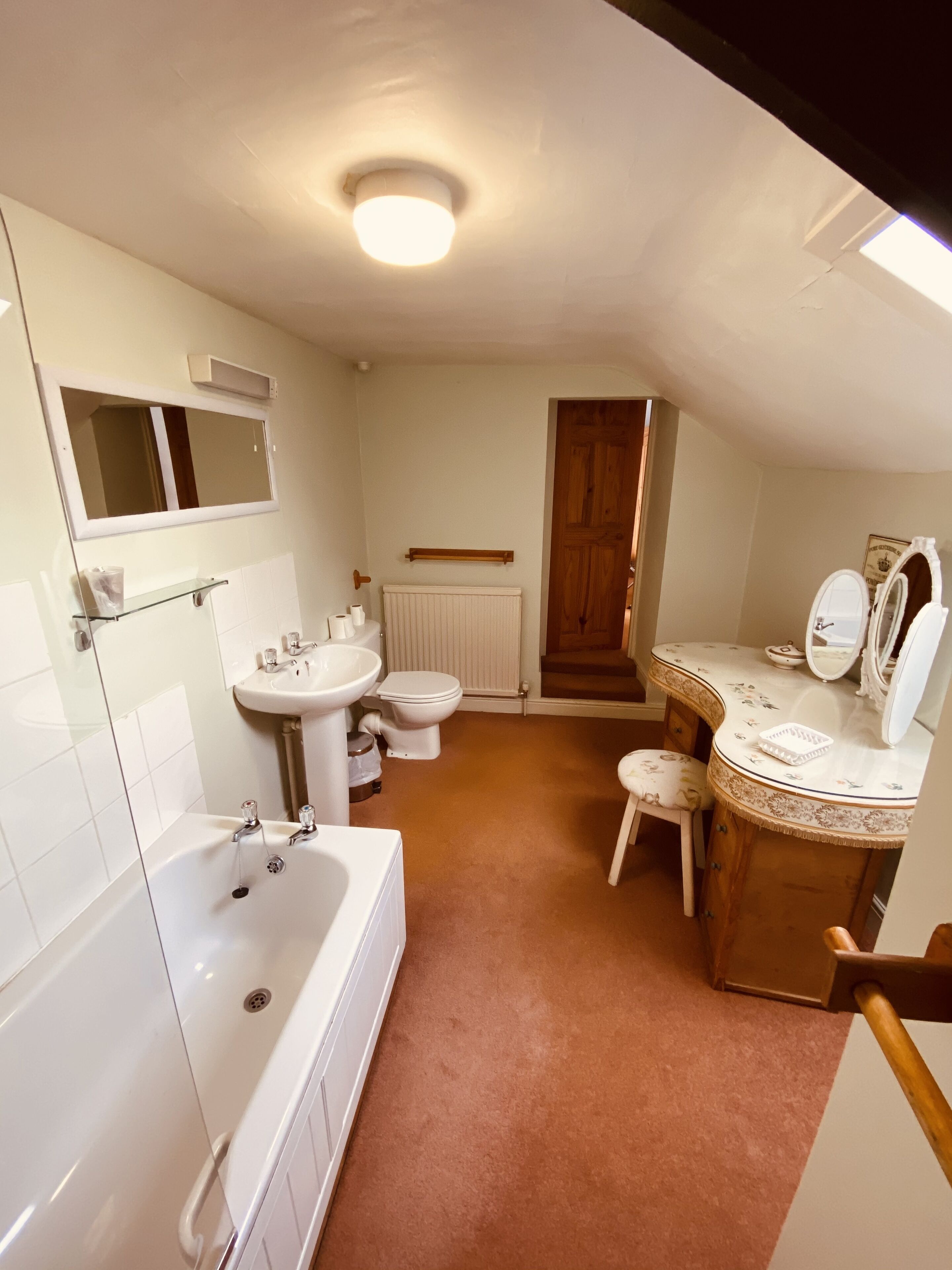 Ein Badezimmer mit Badewanne, Waschbecken, Toilette und Waschtisch mit Spiegel.