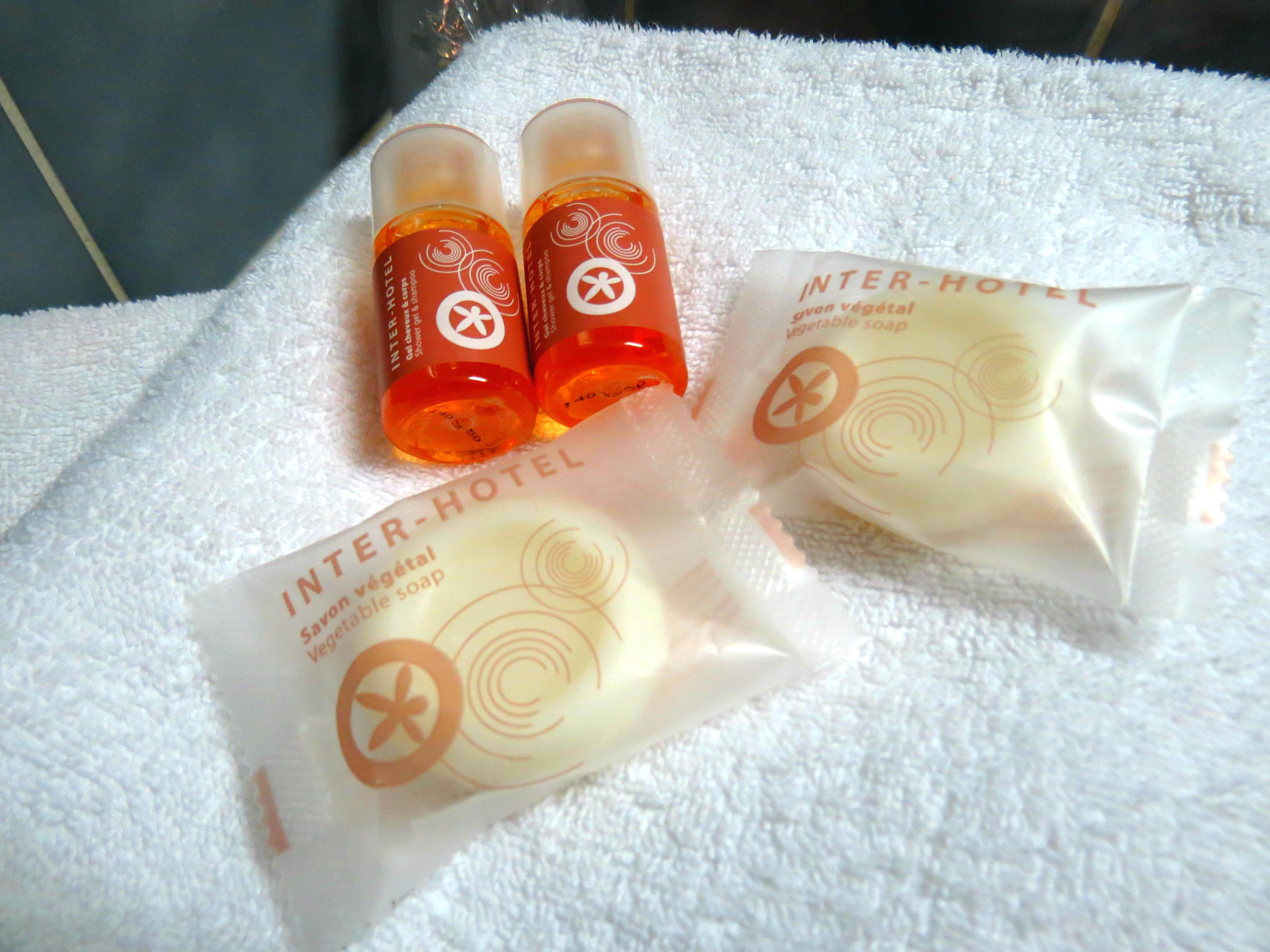 Two bottles and two packages of Inter-Hotel vegetable soap on a white towel.